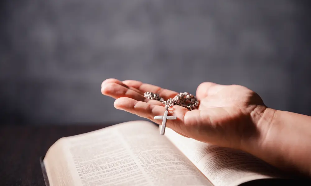 聖經上一隻手上放著十字架項鍊